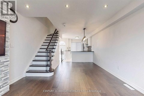 A spacious room with wooden floors and a staircase.