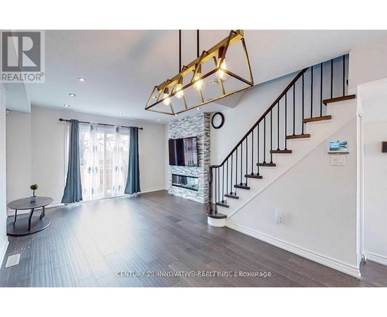 A spacious living room with a staircase and a fireplace.