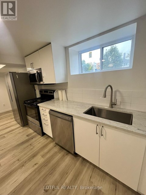 A kitchen with a sink, stove, and cabinets.