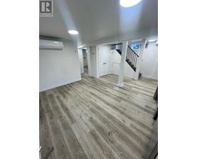 A spacious room with wood flooring and white walls.