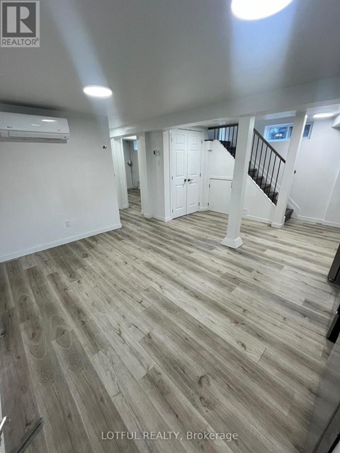 A spacious room with wood flooring and white walls.