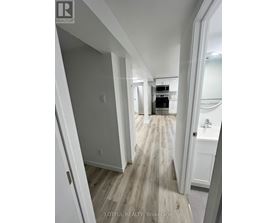 A hallway with wood flooring and white walls.
