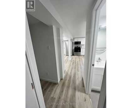 A hallway with wood flooring and white walls.