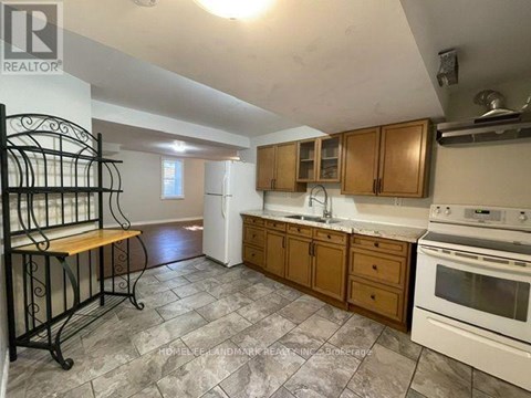 A kitchen with a white stove top oven and wooden cabinets.