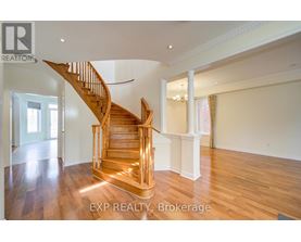 A wooden staircase in a spacious room with EXP REALTY, Brokerage written on the bottom.