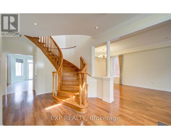 A wooden staircase in a spacious room with EXP REALTY, Brokerage written on the bottom.