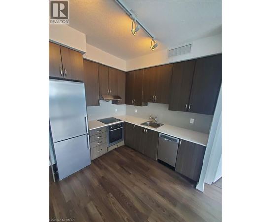 A kitchen with a refrigerator, sink, and stove.