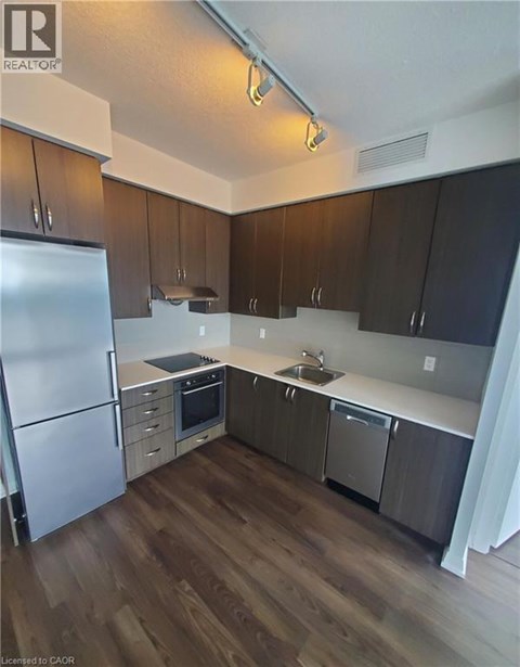 A kitchen with a refrigerator, sink, and stove.