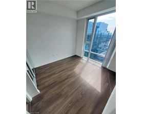 A room with wooden flooring and a large window overlooking a cityscape.