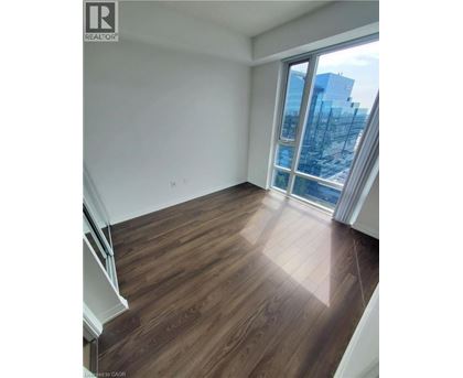 A room with wooden flooring and a large window overlooking a cityscape.
