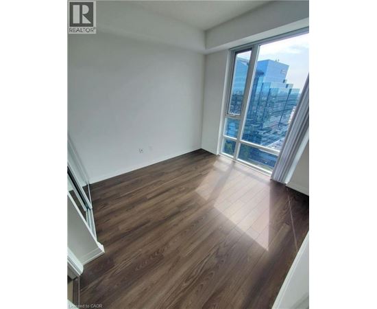 A room with wooden flooring and a large window overlooking a cityscape.