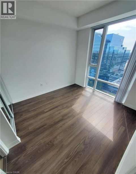 A room with wooden flooring and a large window overlooking a cityscape.