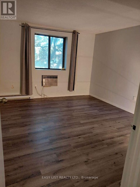 A room with wooden flooring and a window with curtains.