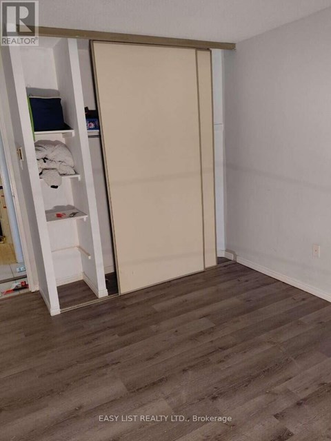 A room with a sliding door and a shelf with towels and a laptop.
