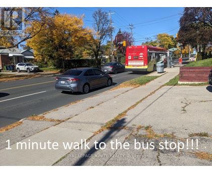 A grey car is parked on the side of the road near a bus stop.