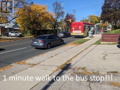 A grey car is parked on the side of the road near a bus stop.