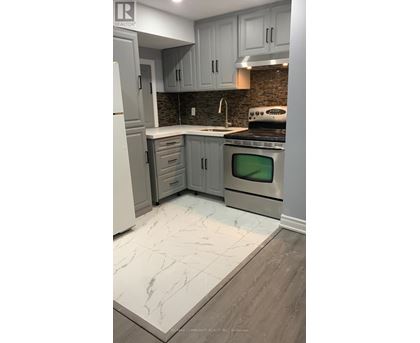 A kitchen with a white refrigerator, grey cabinets and a black stove top oven.