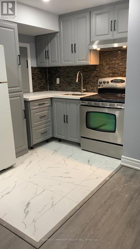 A kitchen with a white refrigerator, grey cabinets and a black stove top oven.