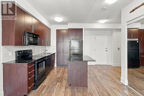 A kitchen with dark wood cabinets and black appliances.