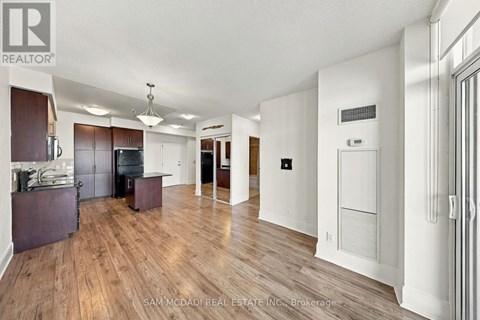 A large open living space with wood flooring and white walls.