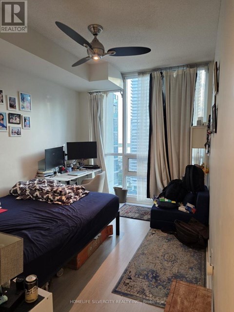 A bedroom with a bed, a fan, a couch, and a television.