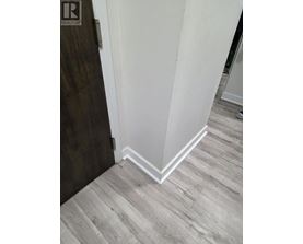 A corner of a room with a wooden floor and white walls.