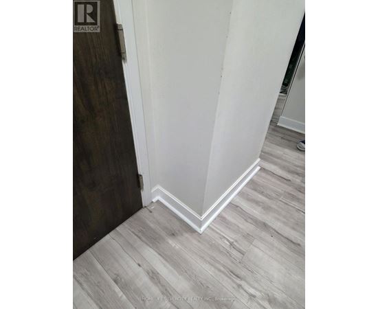 A corner of a room with a wooden floor and white walls.