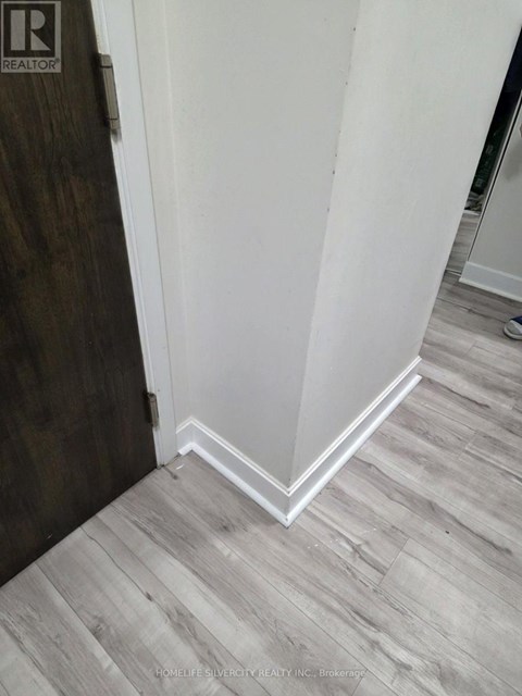 A corner of a room with a wooden floor and white walls.