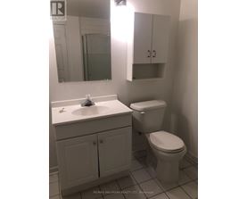 A white bathroom with a toilet, sink and medicine cabinet.
