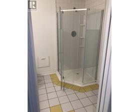 A shower stall with a glass door and a white tile floor.