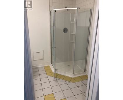A shower stall with a glass door and a white tile floor.