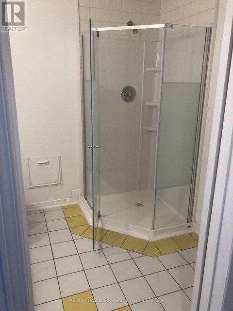 A shower stall with a glass door and a white tile floor.
