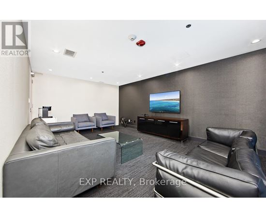 A living room with grey and black leather furniture and a flat screen TV.