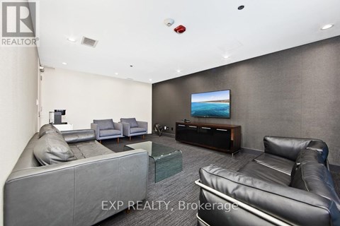 A living room with grey and black leather furniture and a flat screen TV.