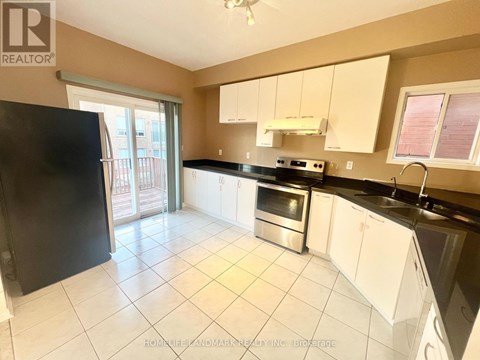 A kitchen with white cabinets and black countertops is on the market.