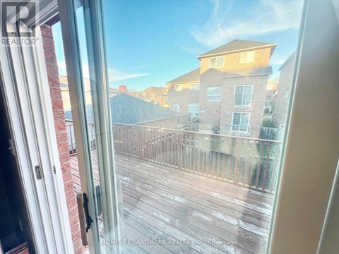 A view from inside a room looking out to a wooden deck and apartment buildings.