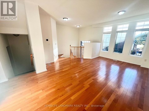 A spacious room with wooden flooring and white walls.