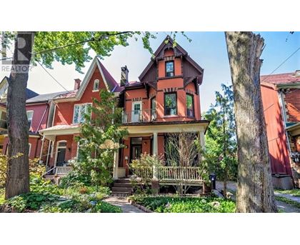 A Victorian style house with a red roof and a porch.