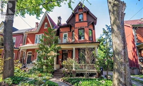A Victorian style house with a red roof and a porch.