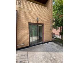 A brick building with a glass door and a small camera on the wall.