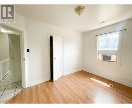 A room with a wooden floor and a window with blinds.