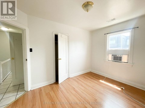 A room with a wooden floor and a window with blinds.