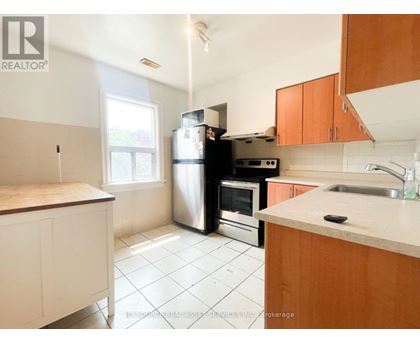A kitchen with white tiles and wooden cabinets.