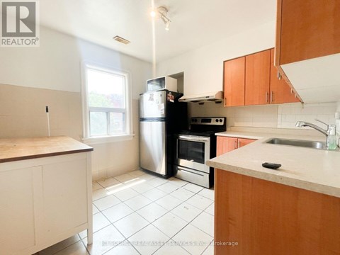 A kitchen with white tiles and wooden cabinets.