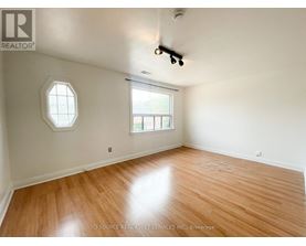 A room with a wooden floor and a window with a view of a building.