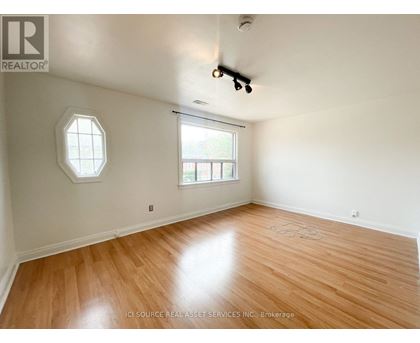 A room with a wooden floor and a window with a view of a building.