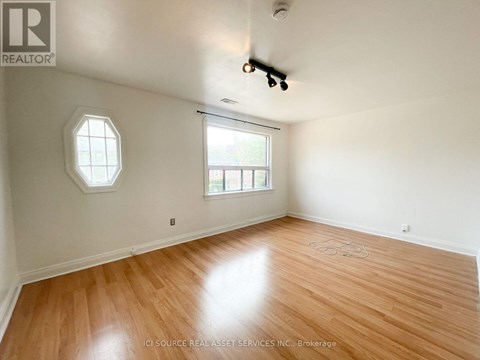 A room with a wooden floor and a window with a view of a building.