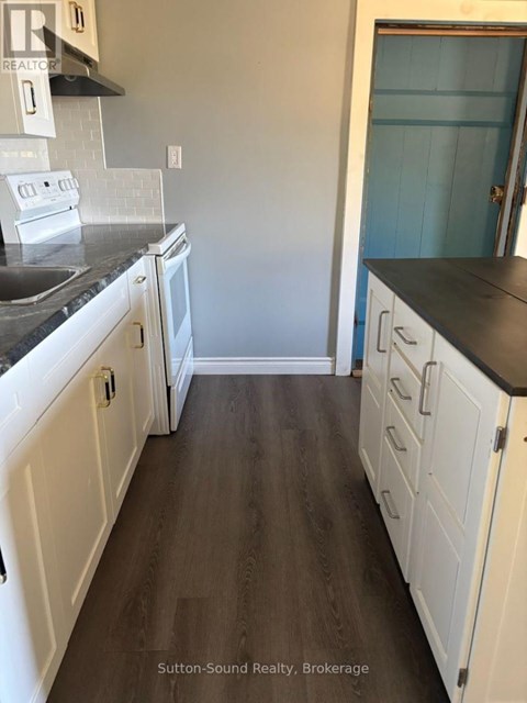 A kitchen with white cabinets and a black countertop.