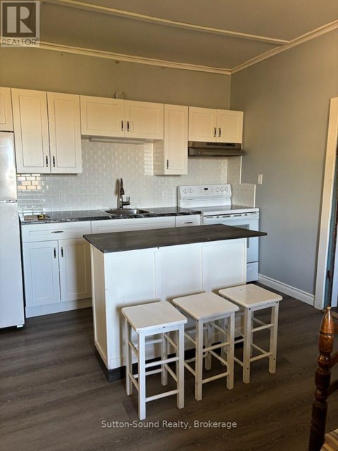 A kitchen with white cabinets and a black countertop.