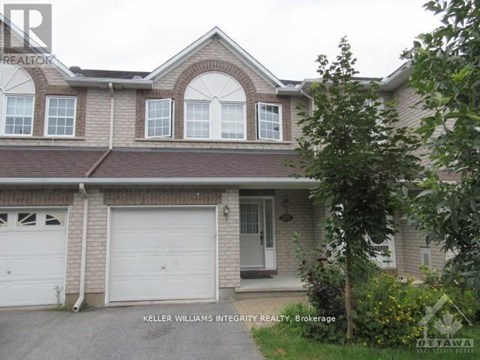 A house with a garage and a tree in front.